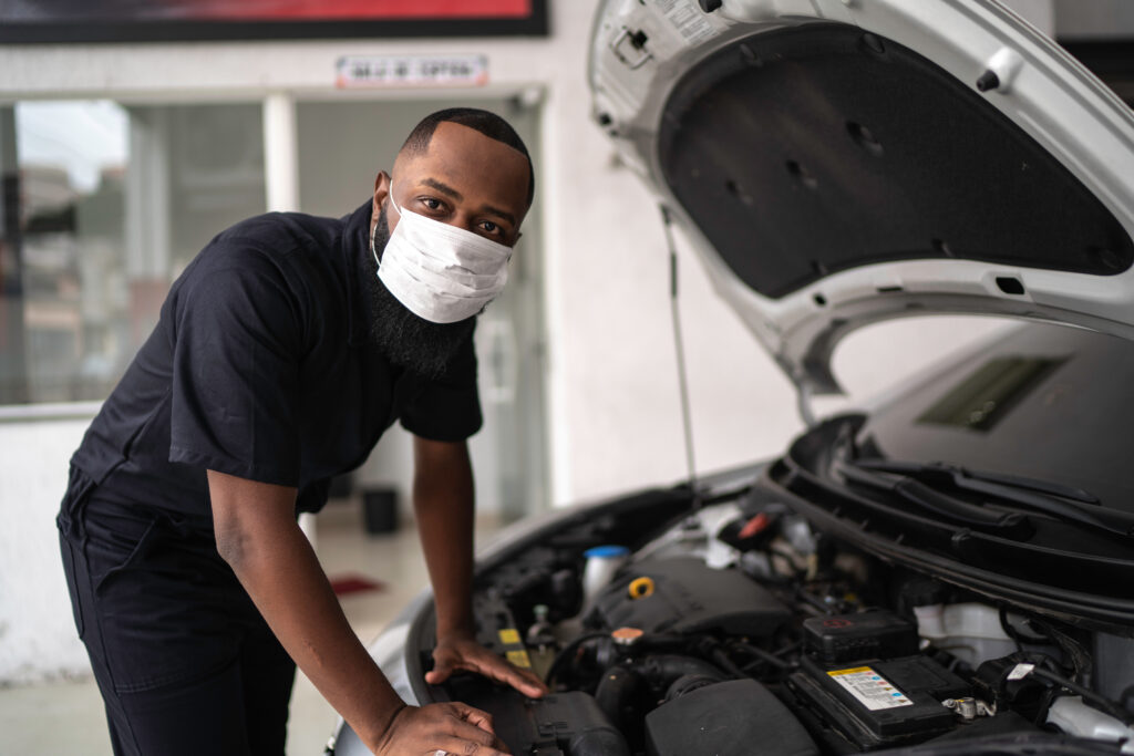 Portrait of auto mechanic man with face mask at auto repair shop